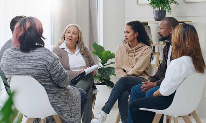 A group of six diverse individuals sitting in a circle and talking amongst each other